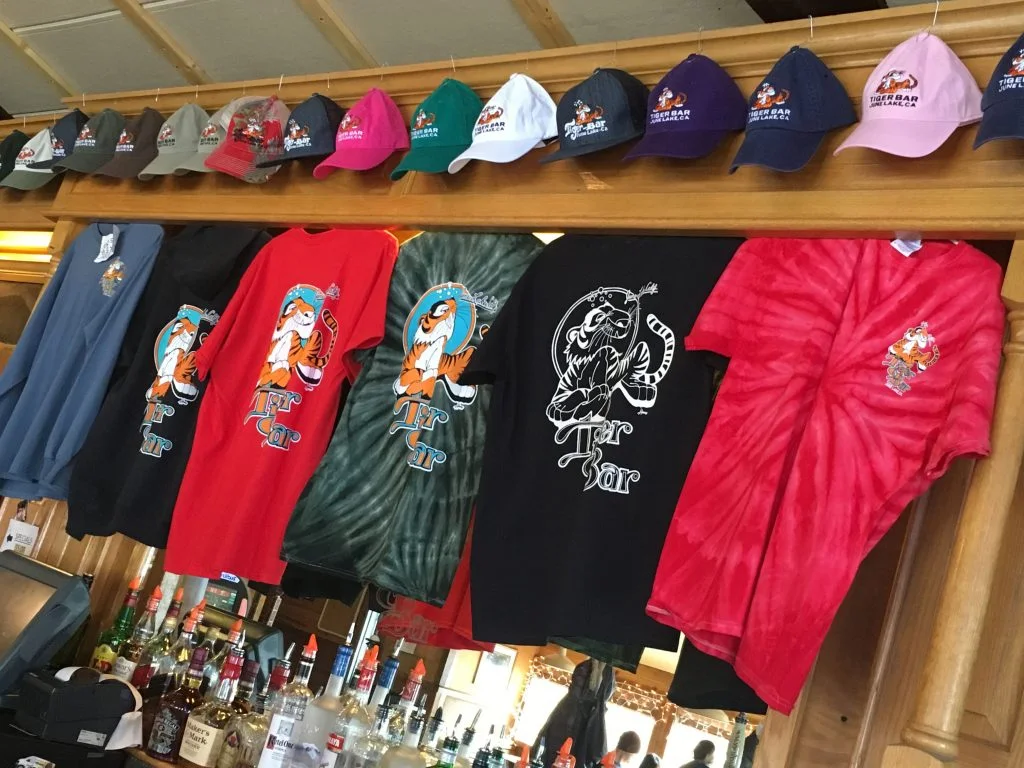 Tiger Bar caps and t-shirts pegged along the rail above the back bar, bottles and string lights on the shelves below