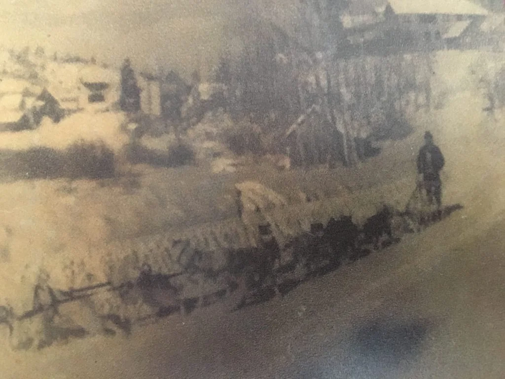 A faded sepia photograph framed on the wall of the bar: a horse-drawn wagon on a dirt road through early June Lake